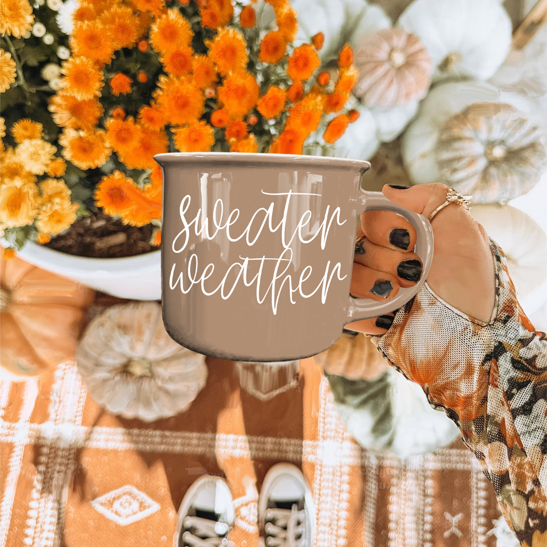 Sweater Weather mug held over orange mums and pumpkins