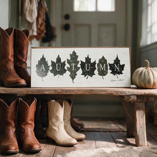 Autumn wood sign with leaves on a rustic bench in a farmhouse entryway with boots and a pumpkin