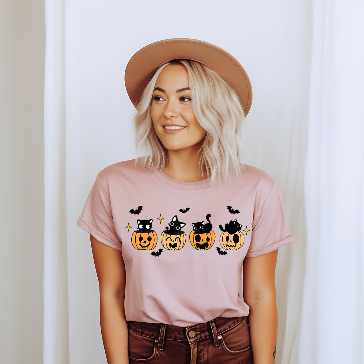 Woman in a hat wearing the pink black cat pumpkin Halloween t-shirt