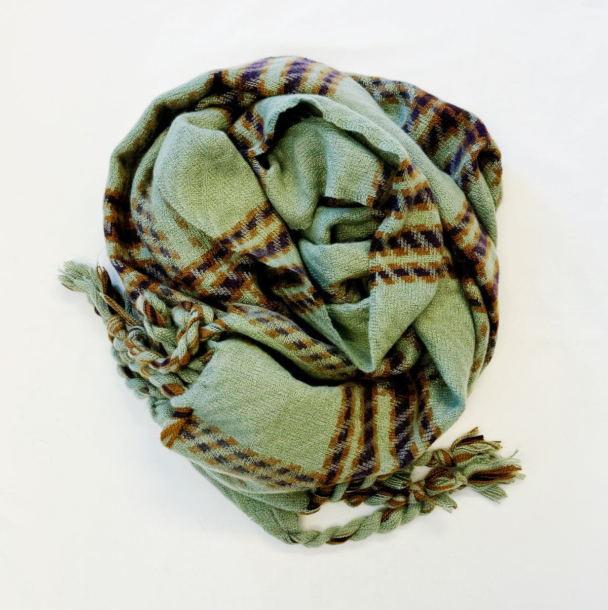 Sage green plaid scarf with braided fringe, loosely folded on white