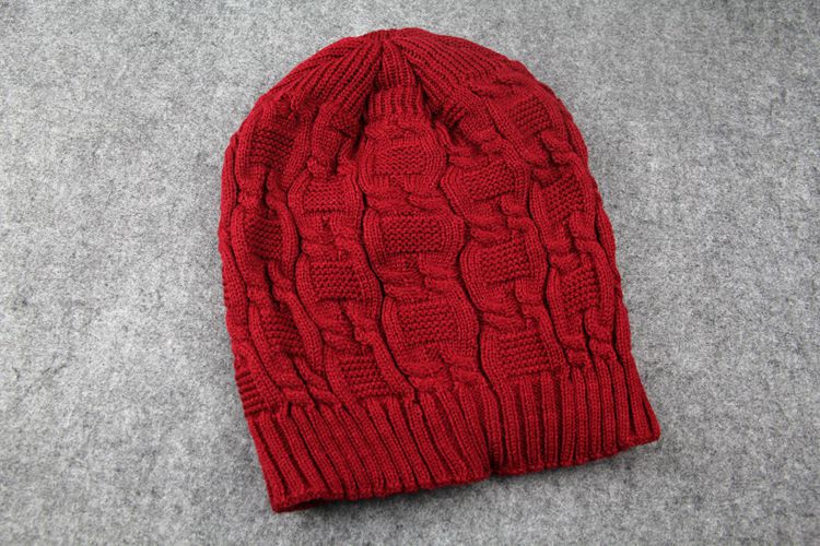 Red cable knit slouchy beanie on a gray surface