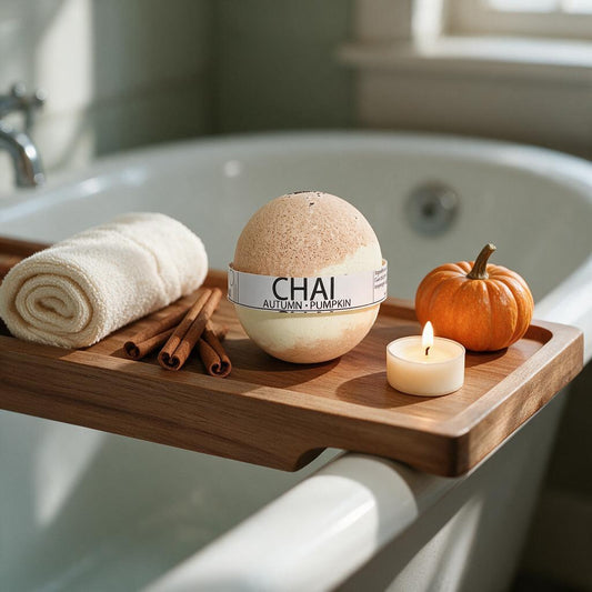Chai autumn pumpkin bath bomb on a wooden bath tray with a rolled towel, cinnamon sticks, a candle and a mini pumpkin