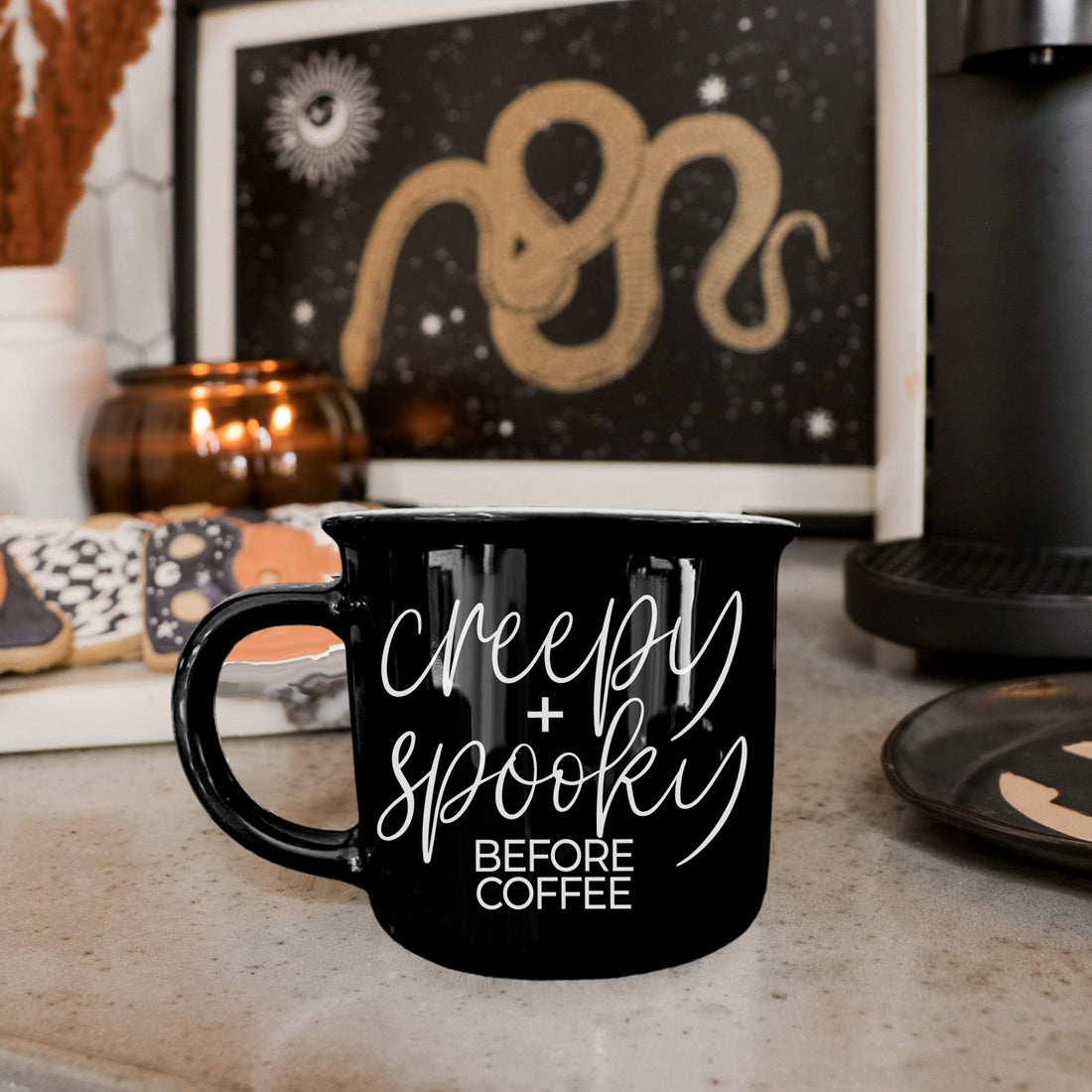 Black Creepy and Spooky Before Coffee mug on a kitchen counter with Halloween art