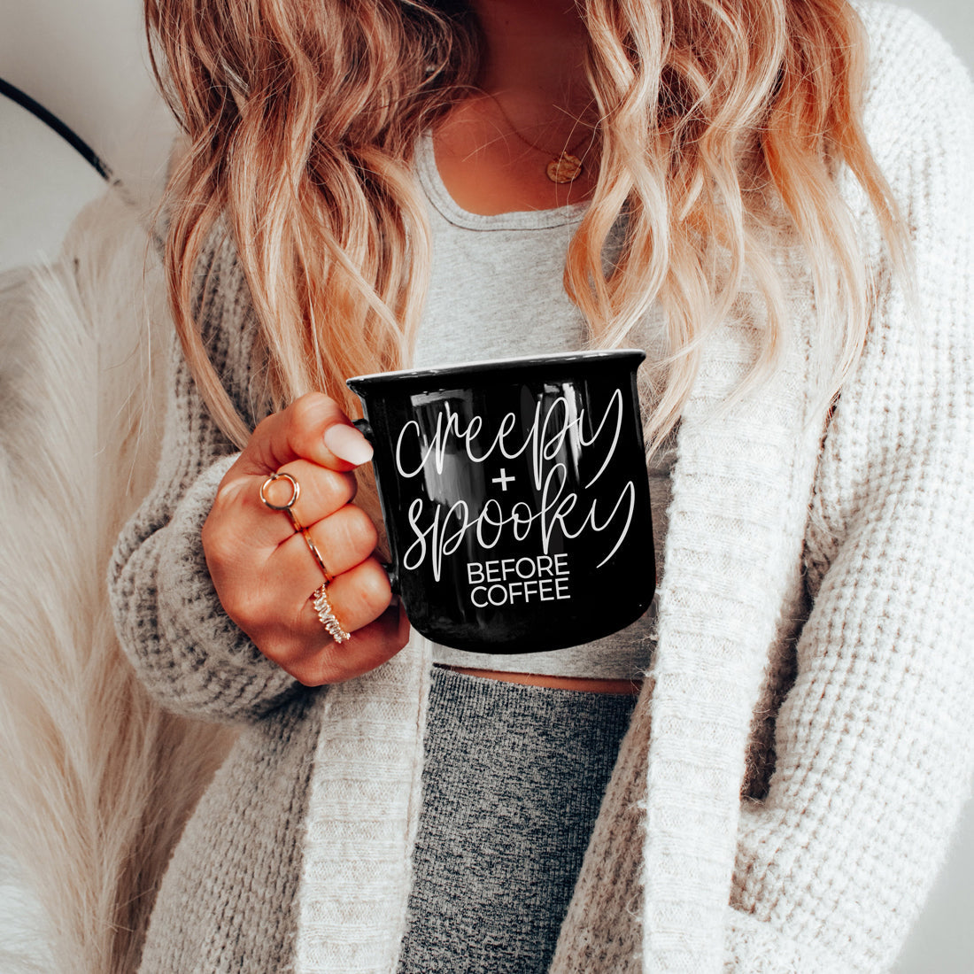 Woman in a cream cardigan holding the Creepy and Spooky mug