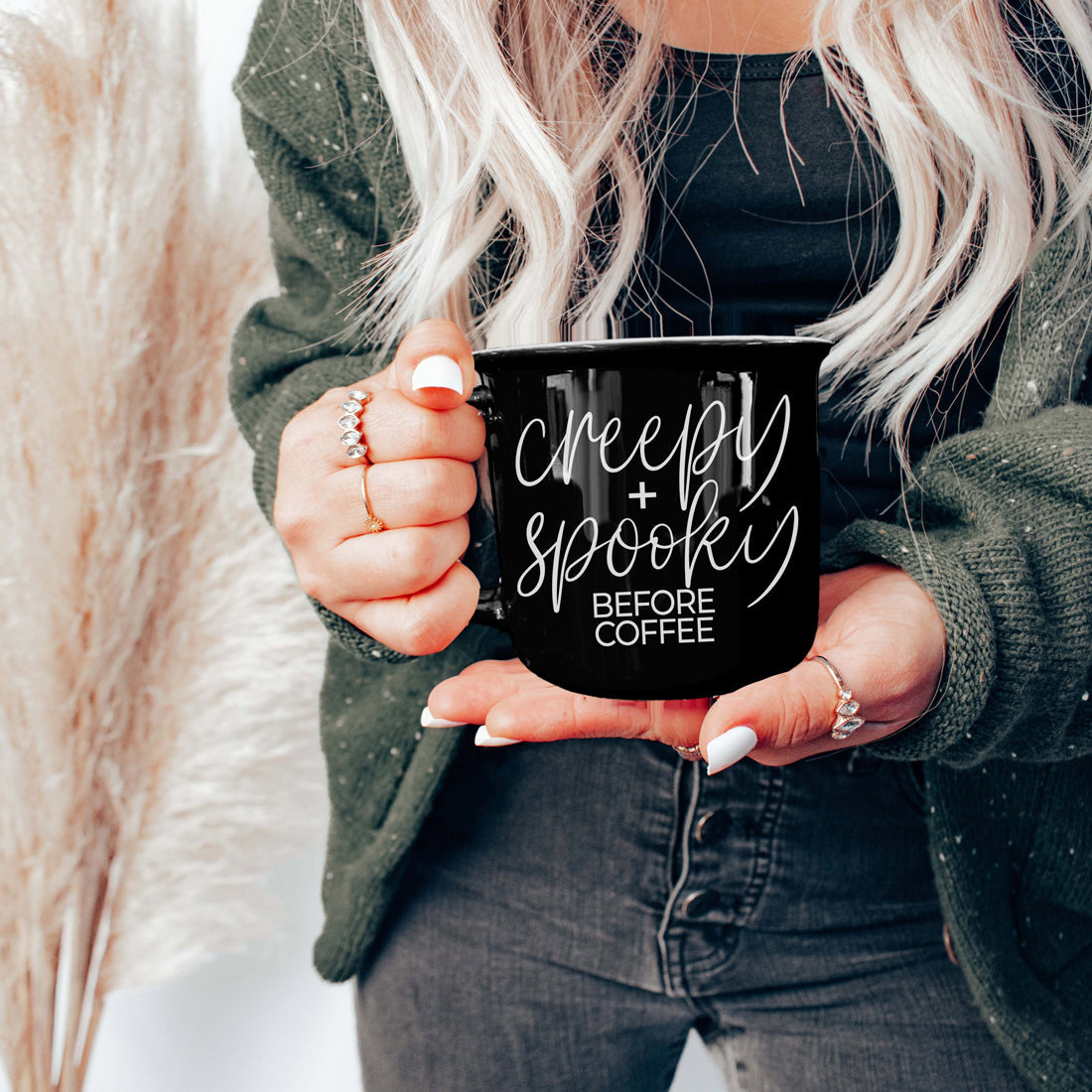 Woman in a green cardigan holding the Creepy and Spooky Before Coffee mug