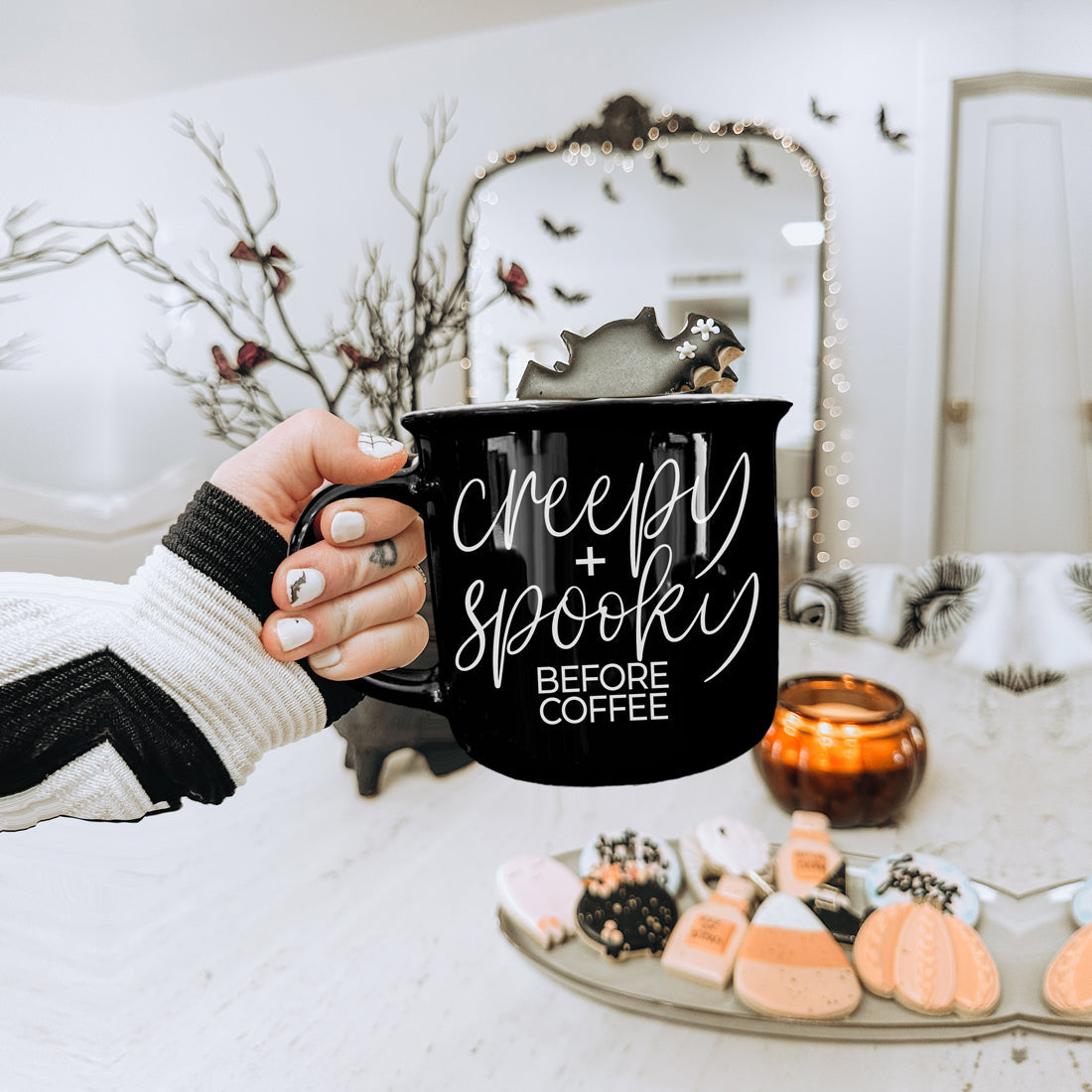 Creepy and Spooky mug held over a table of Halloween cookies and candles