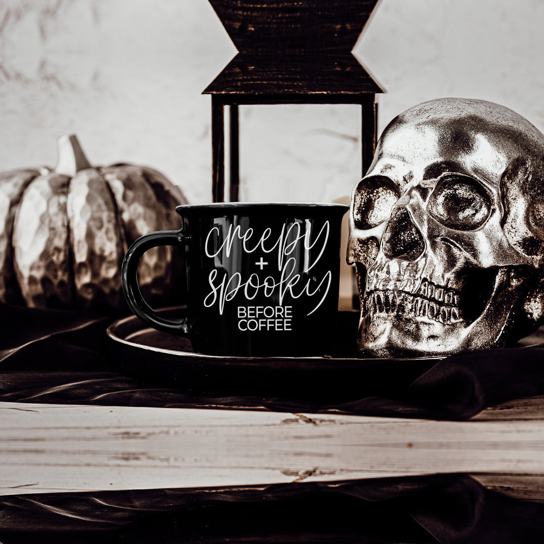 Creepy and Spooky mug on a tray beside a silver skull and lantern