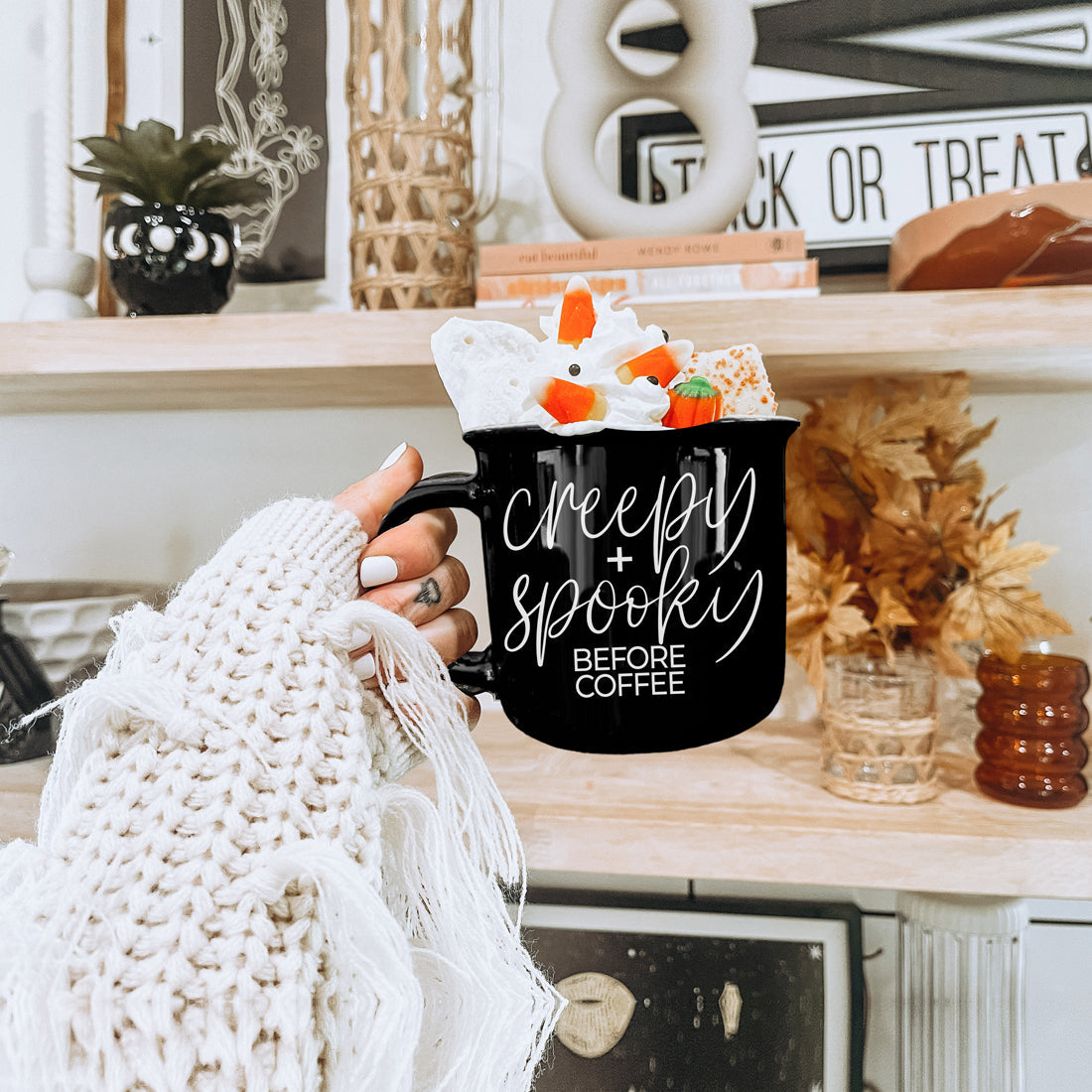 Creepy and Spooky mug filled with candy corn treats on a Halloween shelf
