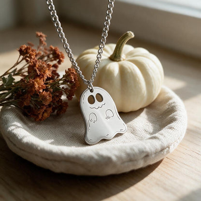 Silver ghost pendant necklace on a linen dish beside a white mini pumpkin