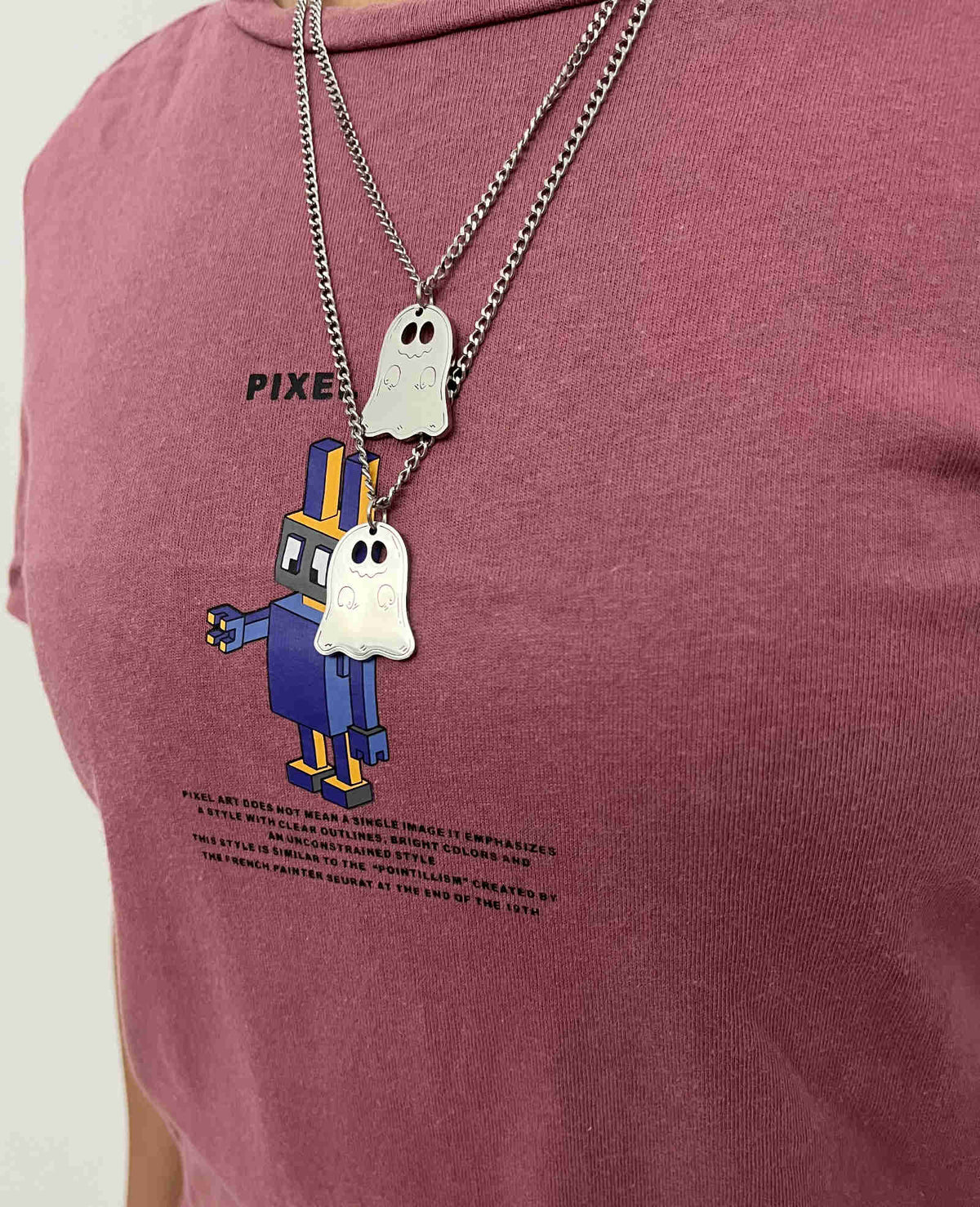 Silver ghost pendant necklace worn over a red graphic t-shirt