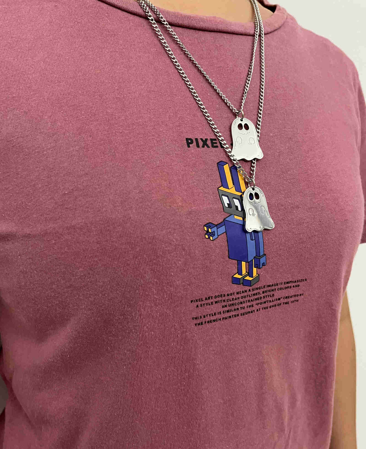 Cute ghost necklace worn layered over a red t-shirt