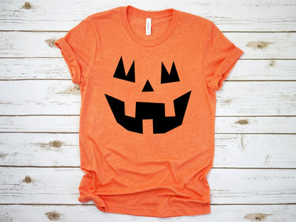 Orange jack-o-lantern face t-shirt laid flat on white wood