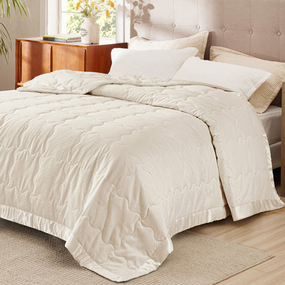 Ivory down alternative blanket with satin trim covering a king bed