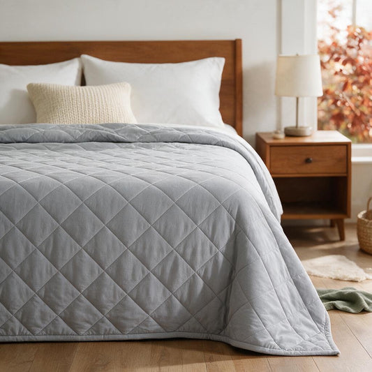 Grey diamond-quilted Eddie Bauer blanket spread over a twin bed with a wooden headboard and nightstand
