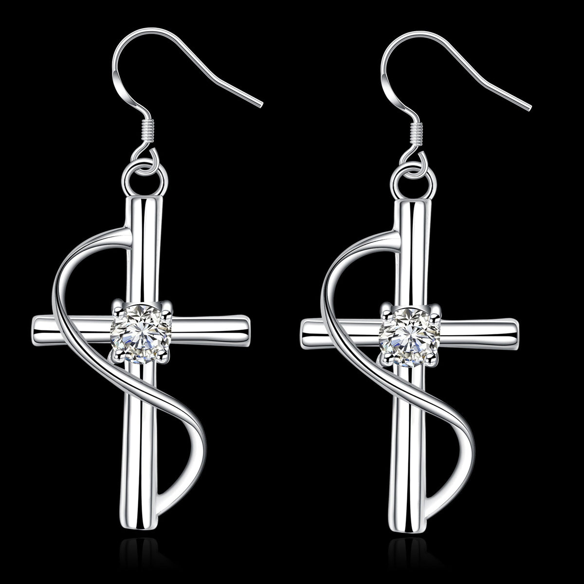 Pair of silver cross dangle earrings with crystal on a black background