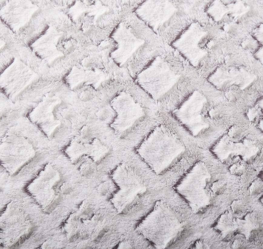 Close-up of the embossed geometric pattern on the white and purple faux fur throw