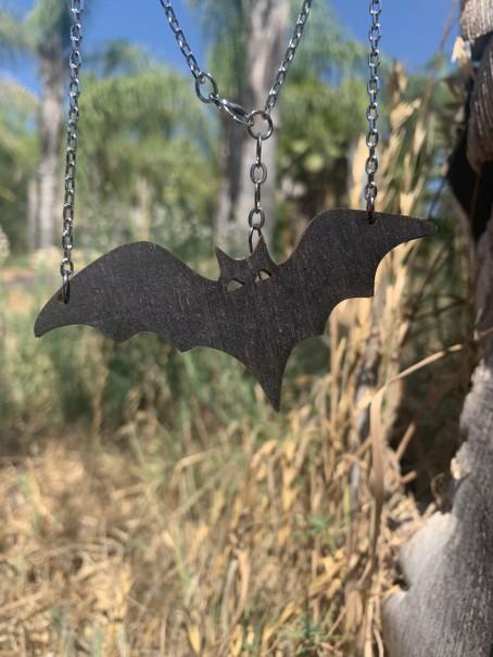 Close-up of the black wooden bat pendant hanging on its chain