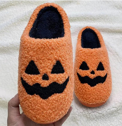 Orange fuzzy jack-o-lantern slippers held up to show size
