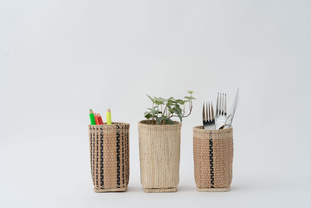 Three handwoven baskets holding pencils, a plant and cutlery