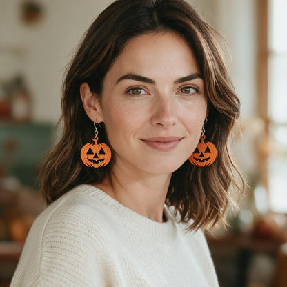 Woman wearing the orange wooden jack-o-lantern dangle earrings with a cream sweater