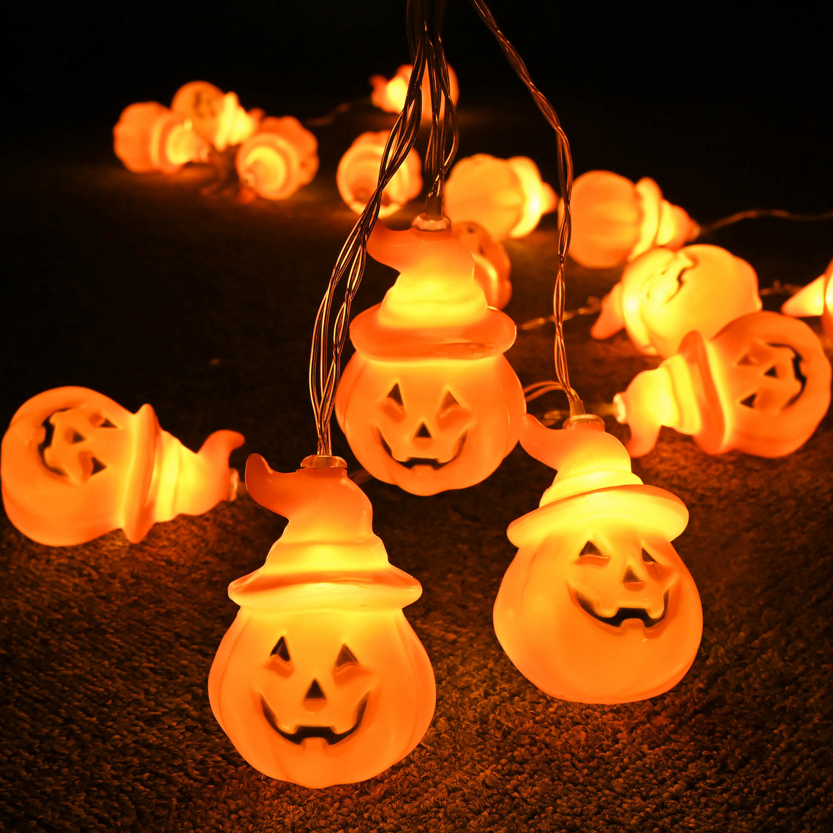 Close-up of glowing jack-o-lantern string lights in the dark