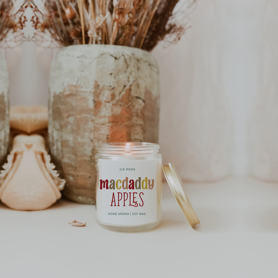 Macdaddy Apples candle beside a stone vase and dried grass