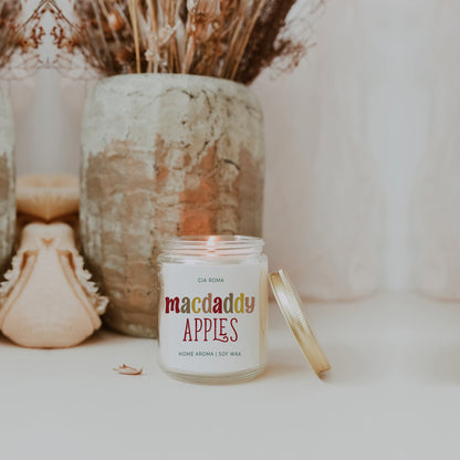 Macdaddy Apples candle beside a stone vase and dried grass