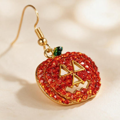 Close-up of a sparkly red-orange rhinestone jack-o-lantern earring with green enamel stem and gold-tone hook