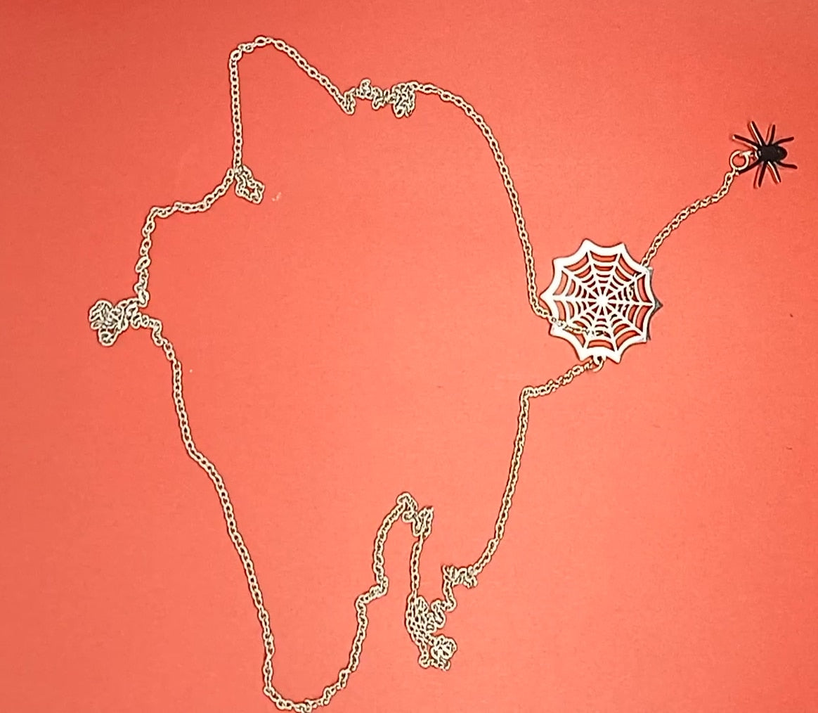 Silver spider web necklace with a hanging spider laid out on red