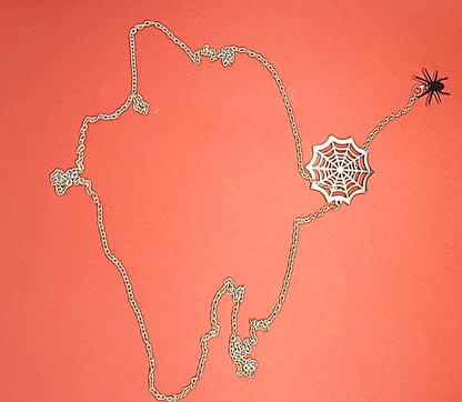 Silver spider web necklace with a hanging spider laid out on red