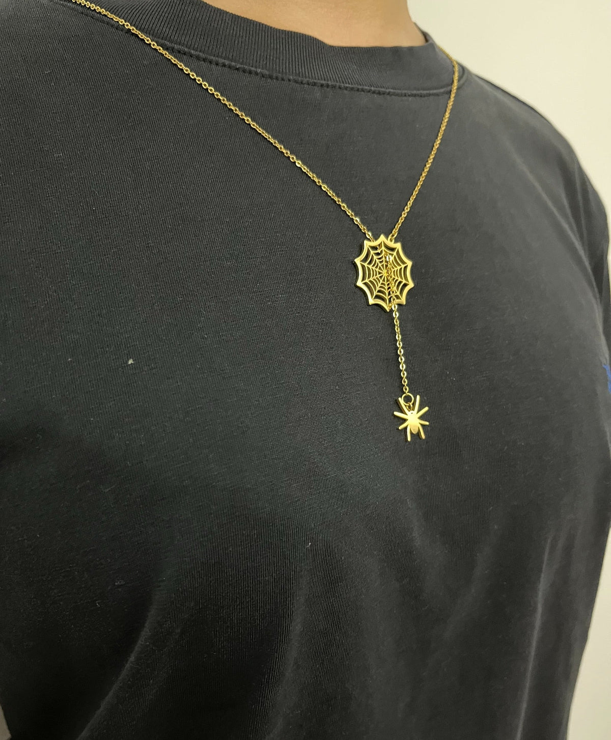 Gold spider web necklace worn over a black t-shirt