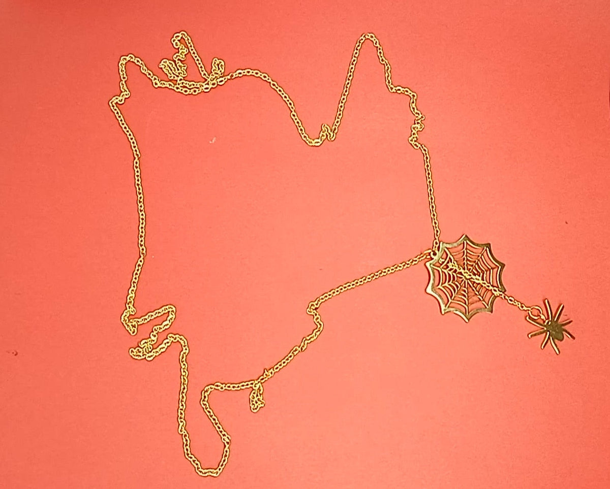 Gold spider web necklace with spider laid out on red