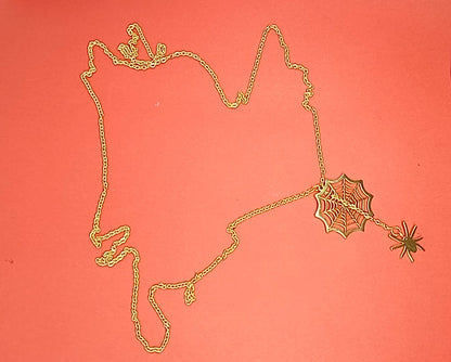 Gold spider web necklace with spider laid out on red