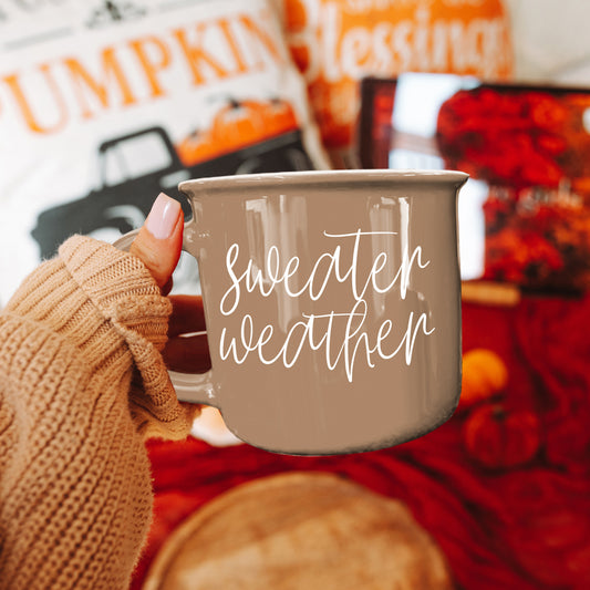 Tan Sweater Weather camp mug held over a red fall tablecloth