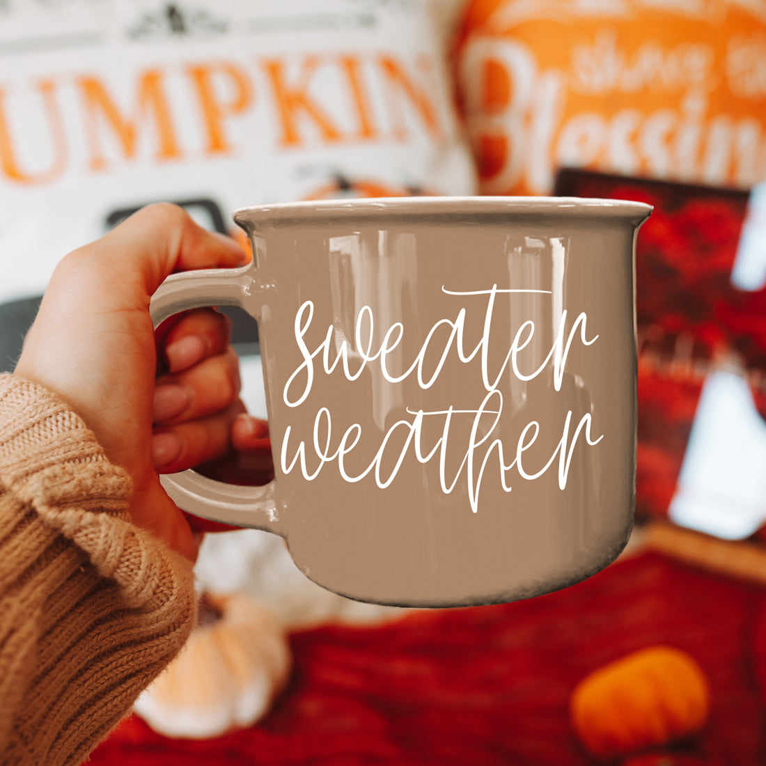 Sweater Weather mug held in front of a Pumpkin sign