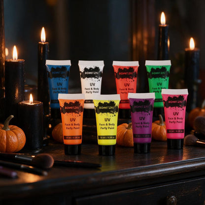 Eight UV neon face and body paint tubes on a Halloween vanity with candles and pumpkins