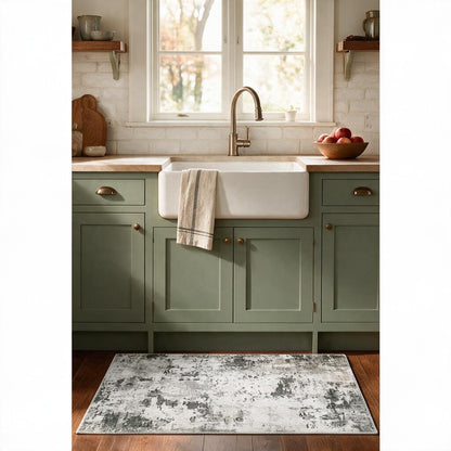 Grey, white and sage abstract washable rug in front of a farmhouse sink with sage green cabinets
