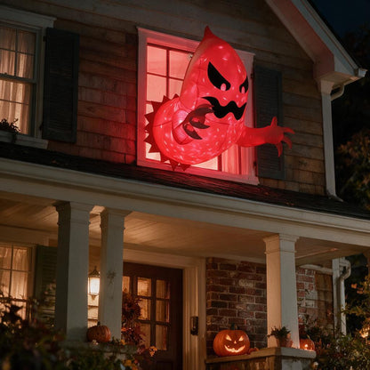 Glowing red inflatable ghost bursting out of an upstairs window of a house decorated for Halloween