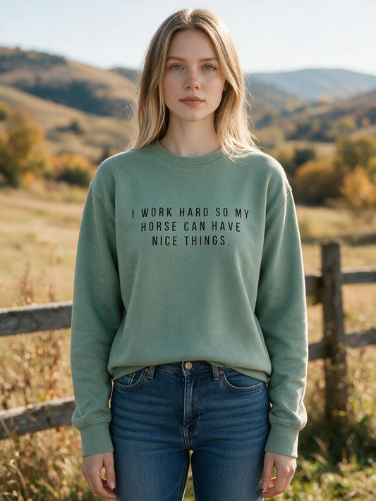Woman wearing the sage I Work Hard So My Horse Can Have Nice Things sweatshirt by a fence